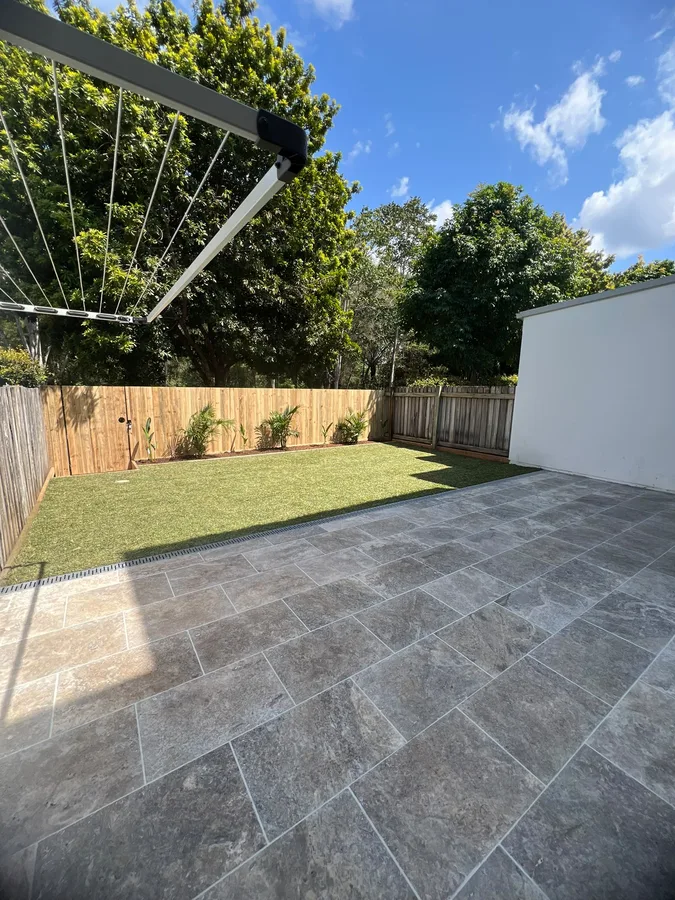Completed paved courtyard connecting a lawn and garden at a residential property